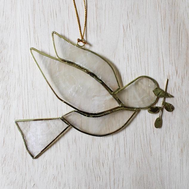 Decorative glass dove with olive branch on a light wooden surface