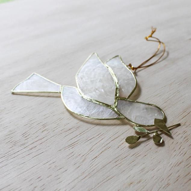 Decorative leaf-shaped object with gold accents on a light wooden surface