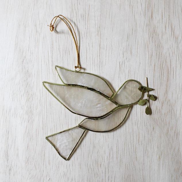 Decorative glass dove with olive branch on a light wooden surface