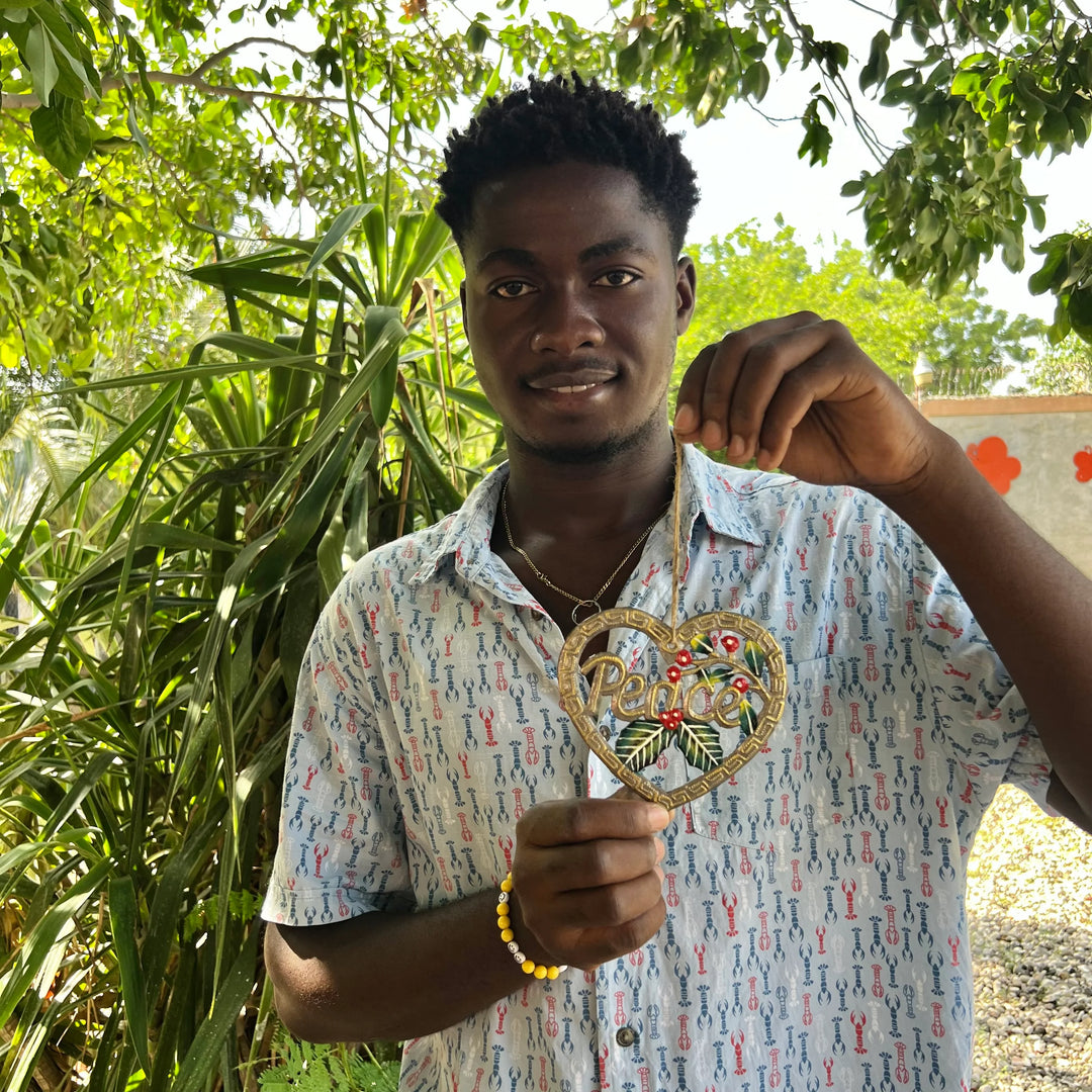 young artisan holding a metal art ornament with the word "peace".