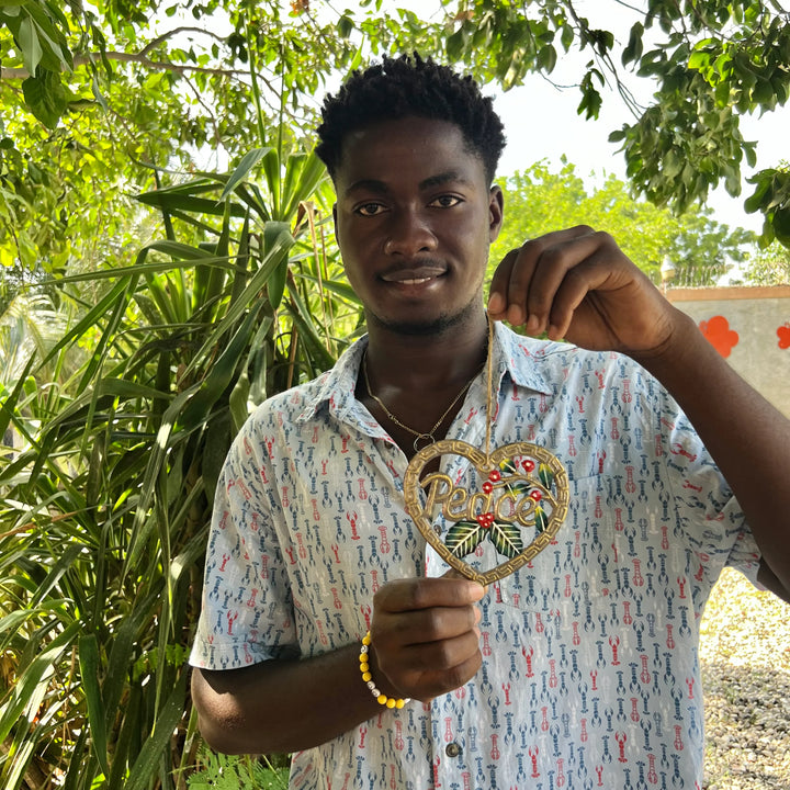 young artisan holding a metal art ornament with the word "peace".