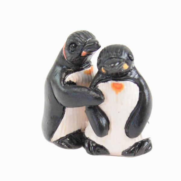 Two penguin figurines holding hands on a white background