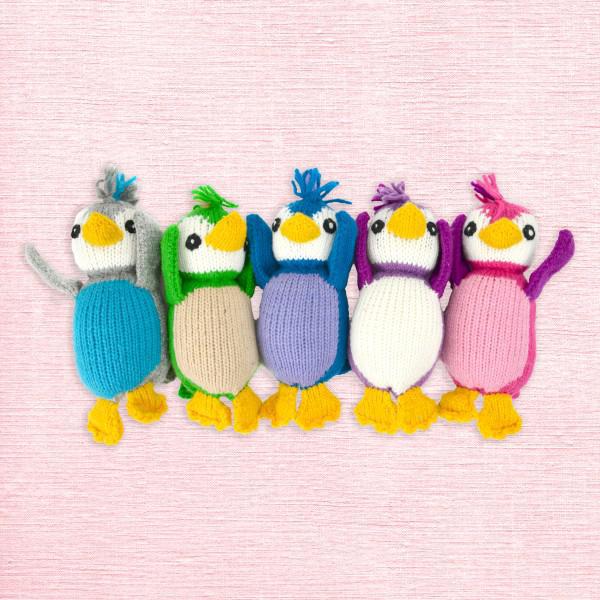 Five colorful knitted penguin toys on a pink textured background