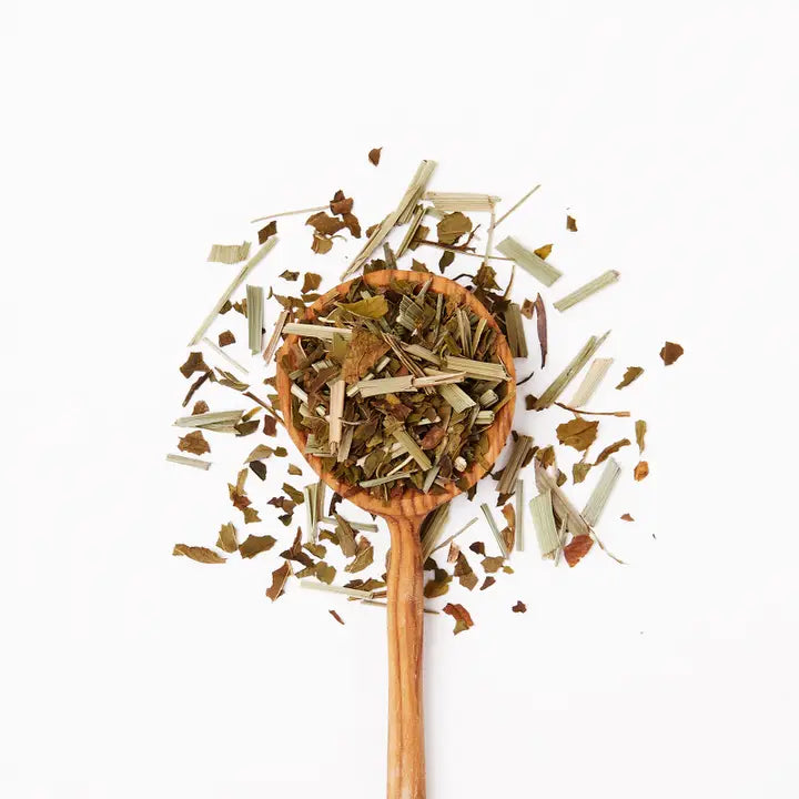 Wooden spoon filled with dried tea on a white background