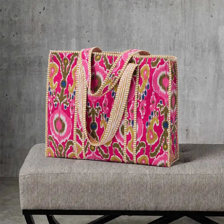 Pink patterned bag on a gray chair with a concrete wall background