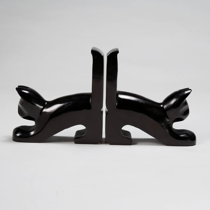 A pair of glossy black kisii stone bookends shaped like stylized black cats facing away from each other, set against a neutral light gray background.
