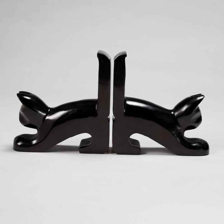 A pair of glossy black kisii stone bookends shaped like stylized black cats facing away from each other, set against a neutral light gray background.