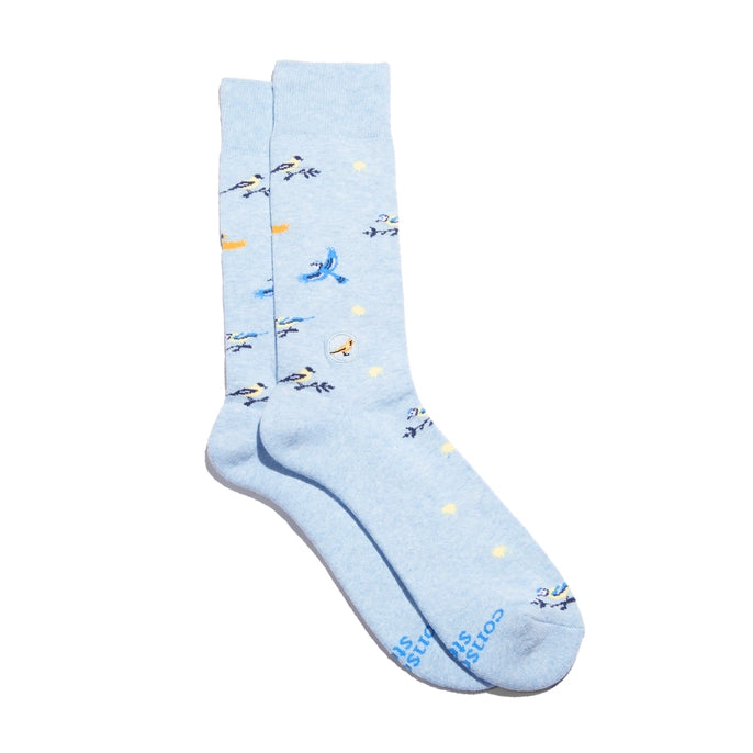 A pair of light blue crew socks with a pattern of flying birds and small yellow stars, featuring the brand name 'The Stop' printed in blue on the toes.