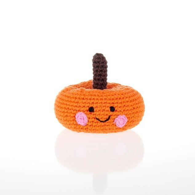 Crocheted pumpkin rattle with a smiling face on a white background