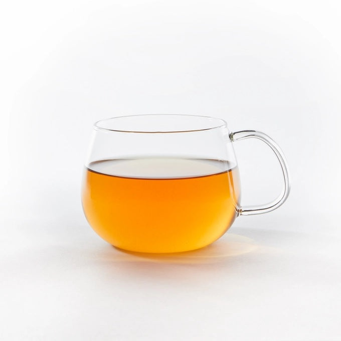 Clear glass mug with pumpkin spice tea on a white background