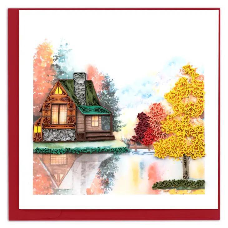 Beautiful hand made quilling card of colorful autumn trees next to a cabin on the water. 