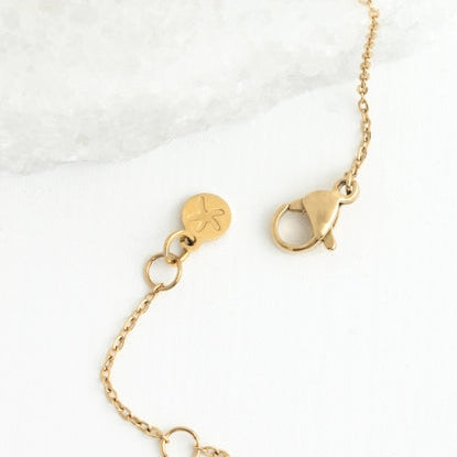 Gold necklace with a clasp on a white marble surface