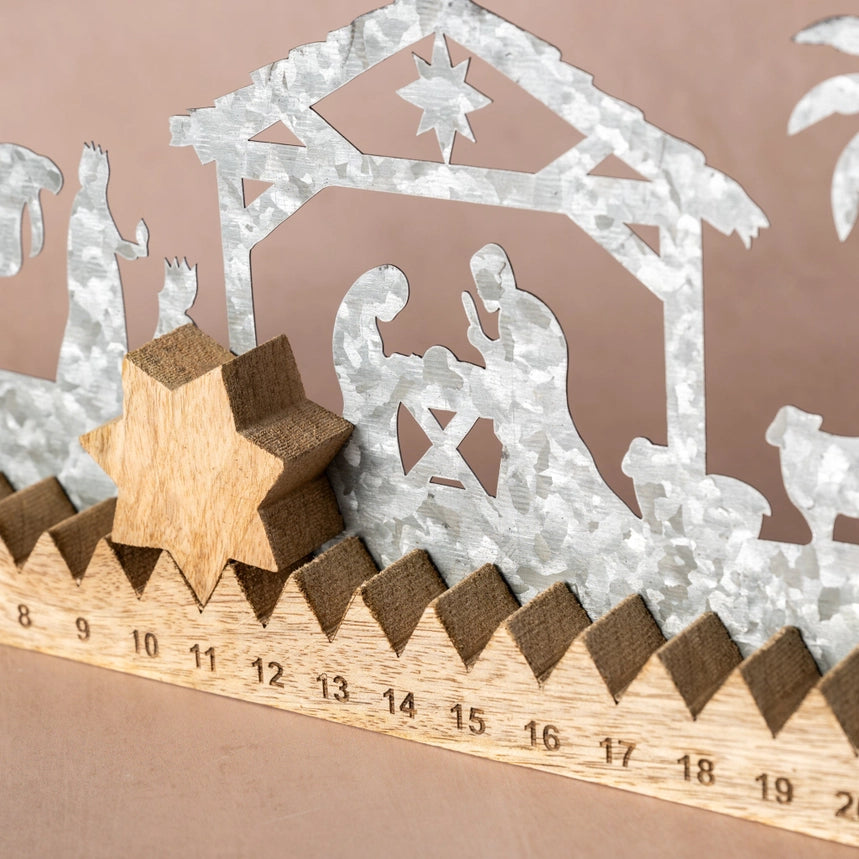 A close-up of a wooden nativity scene decoration with galvanized metal silhouette cutouts and a wooden star, shown on a beige background with a measuring ruler visible along the bottom.