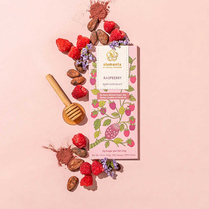 Raspberry dark chocolate bar with raspberries, cocoa powder, and a honey dipper on a pink background