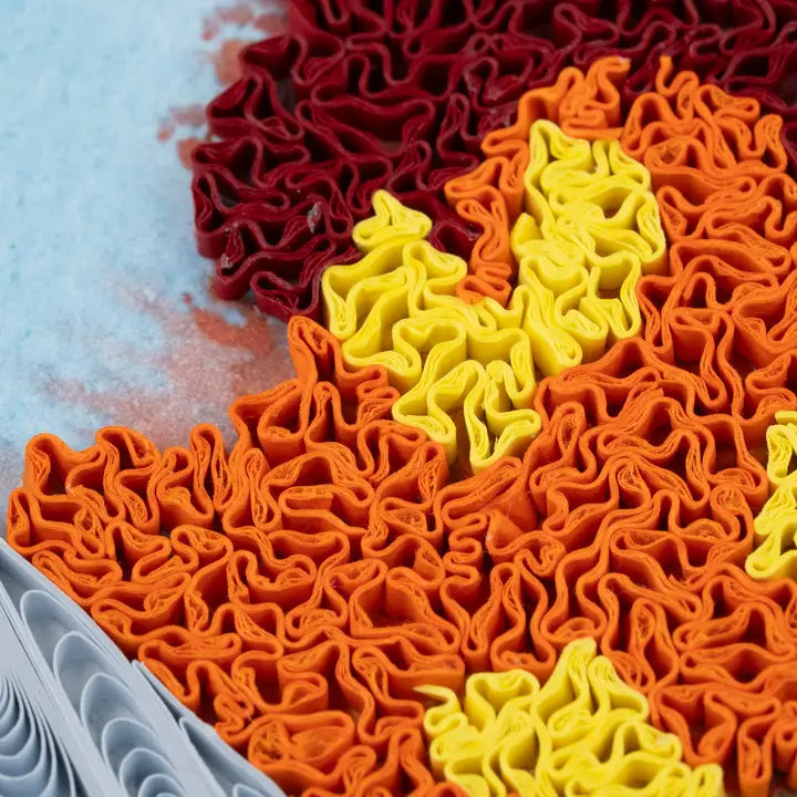 Colorful textured paper in red, orange, and yellow on a grey background