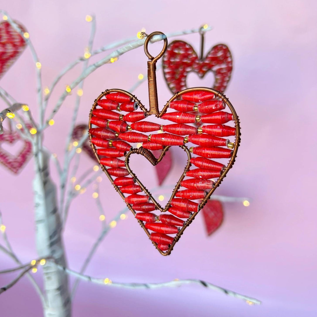 Heart-shaped decorative ornament with red and gold details on a pink background
