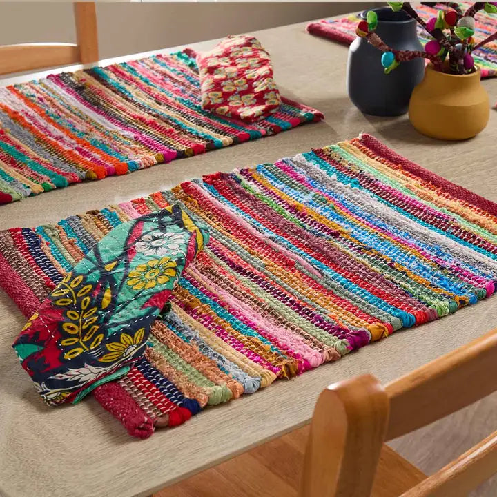 Colorful woven placemats on a table with a chair and decorative items.