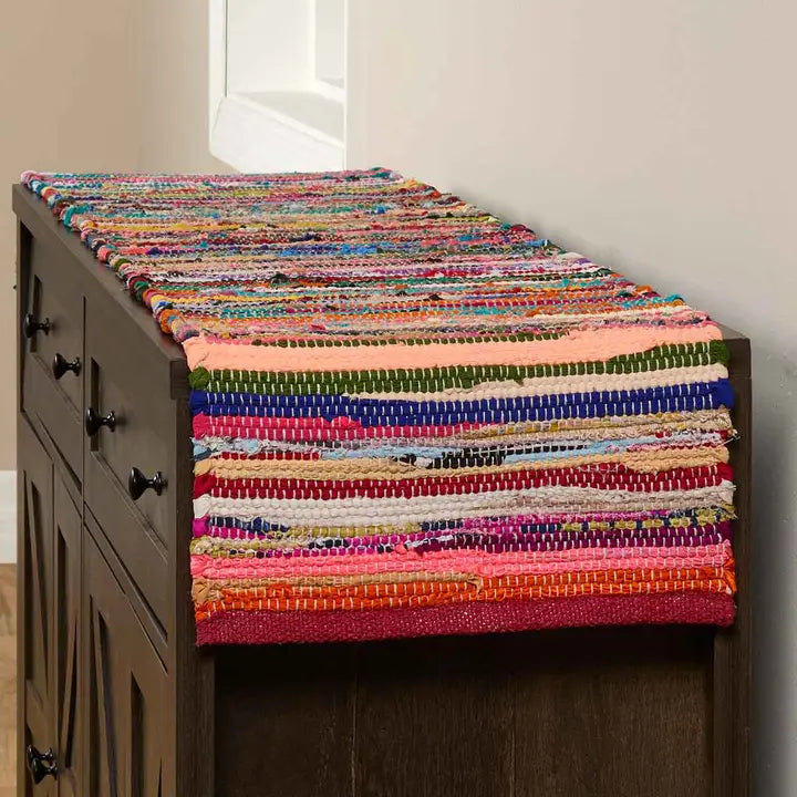 Colorful woven table runner on a wooden cabinet against a neutral wall.