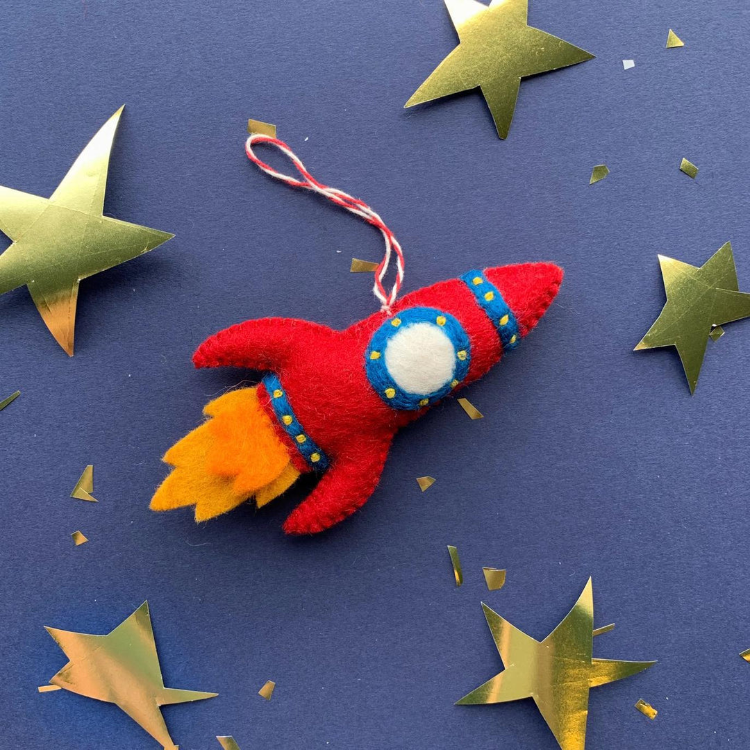 Red felt rocket toy with gold stars on a blue background
