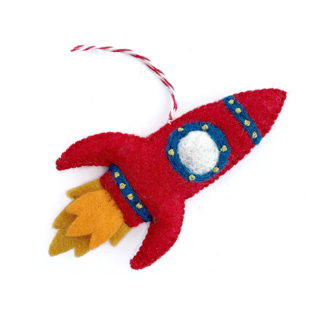 Red felt rocket ship ornament with a white circle and blue details on a white background