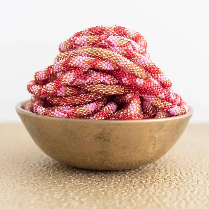 Beaded roll-on bracelet with red, pink, and gold colorings in a bowl.