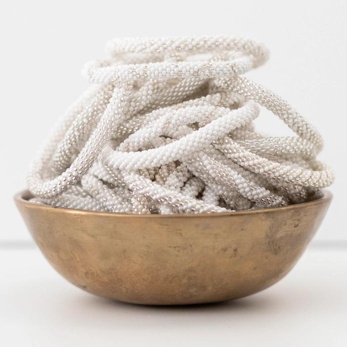 Glass bead roll-on bracelets in pearl white displayed in a bowl.