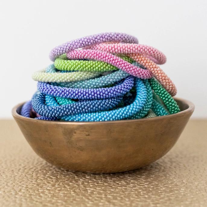 Beaded roll-on bracelets of various colors in a display bowl.