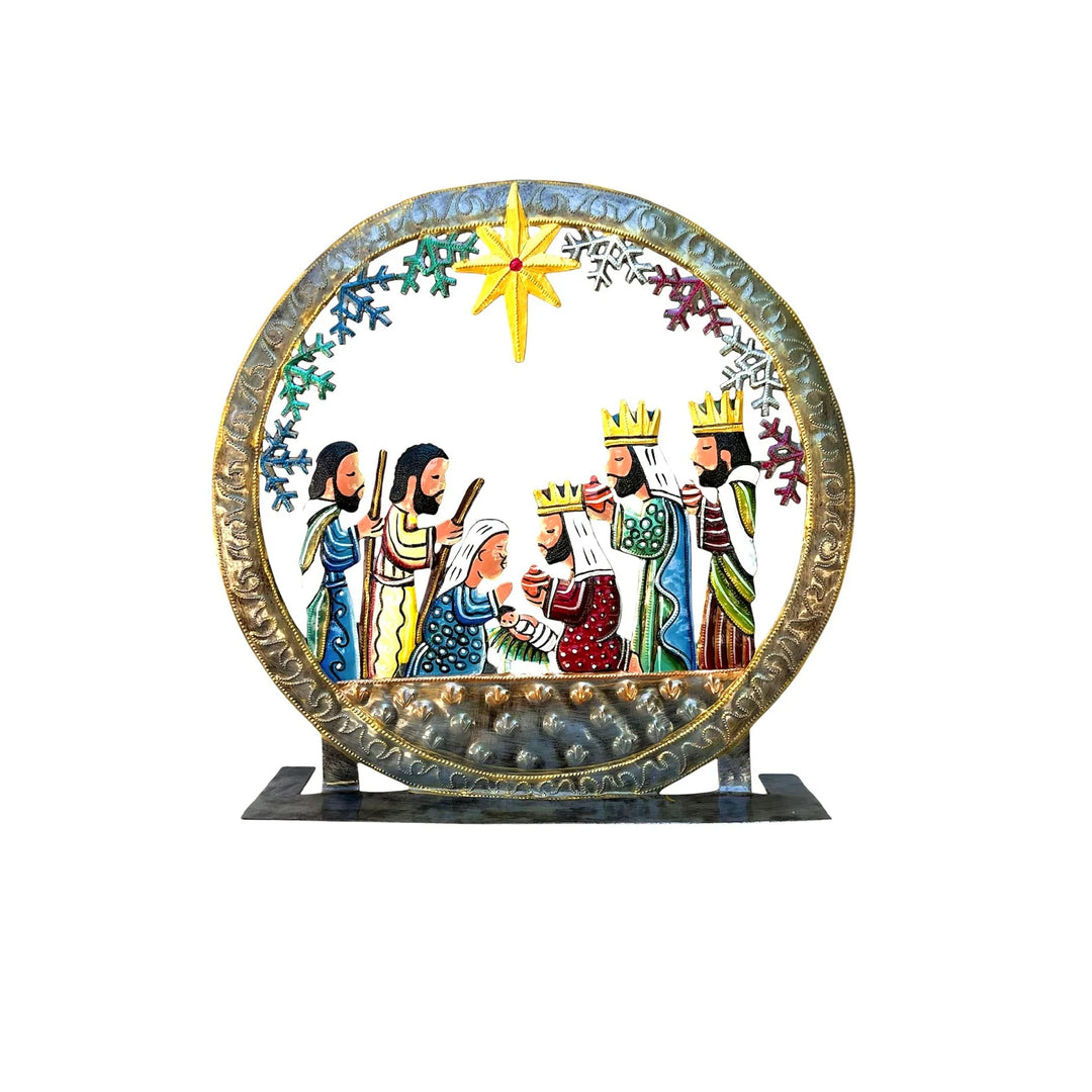 A circular, hand-painted metal Nativity scene plaque on a black display stand, featuring colorful figures and a gold star against a white background.