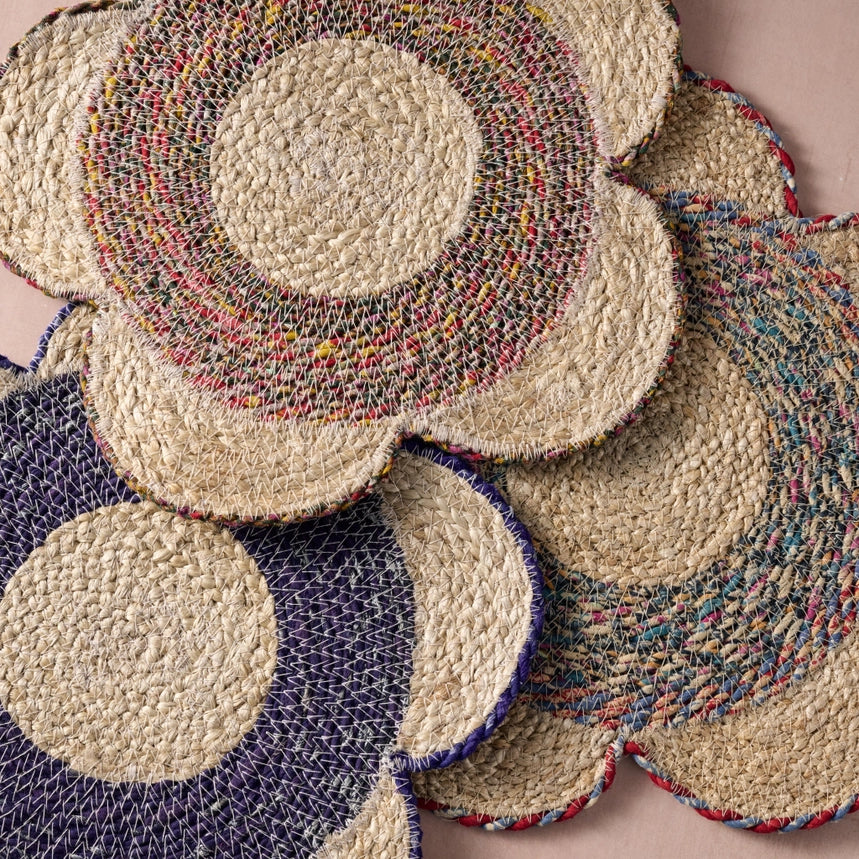 Stack of round woven placemat with multicolored patterns on a neutral background
