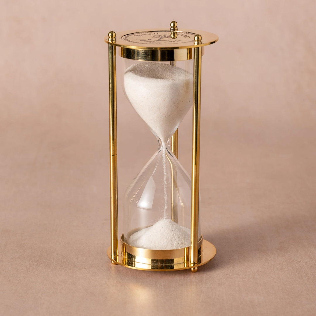 Gold hourglass with sand on a beige background