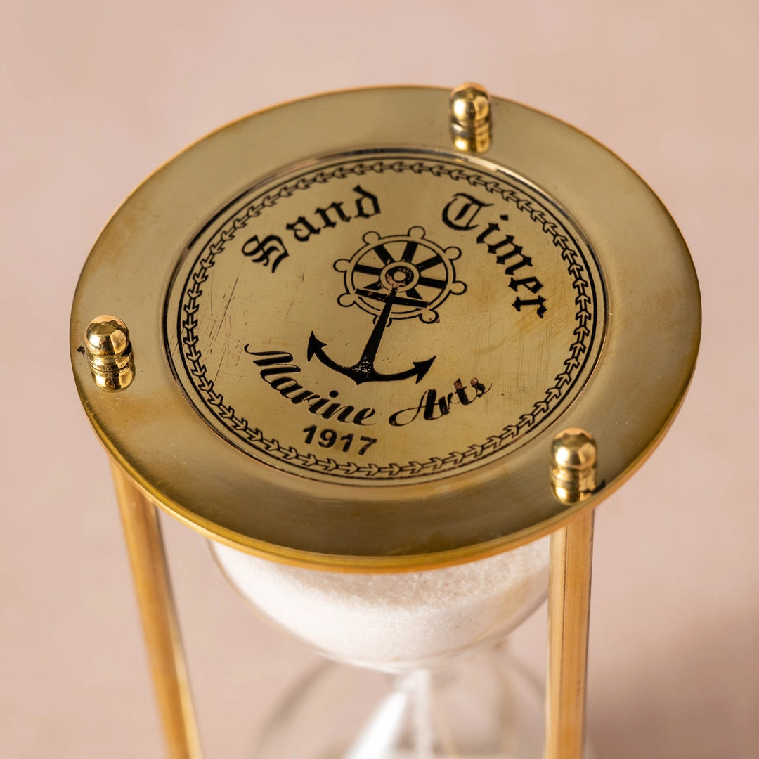 Gold hourglass with 'Hand Timer Marine Avis 1917' text on a beige background