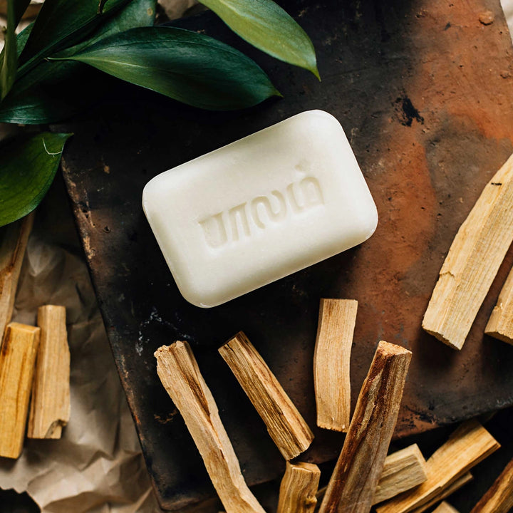 Hand-crafted sandalwood scented bar of soap on top of brick with sandalwood pieces surrounding the bar of soap. 