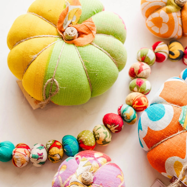 yellow and green and purple sari pumpkins with a sari garland on a white background