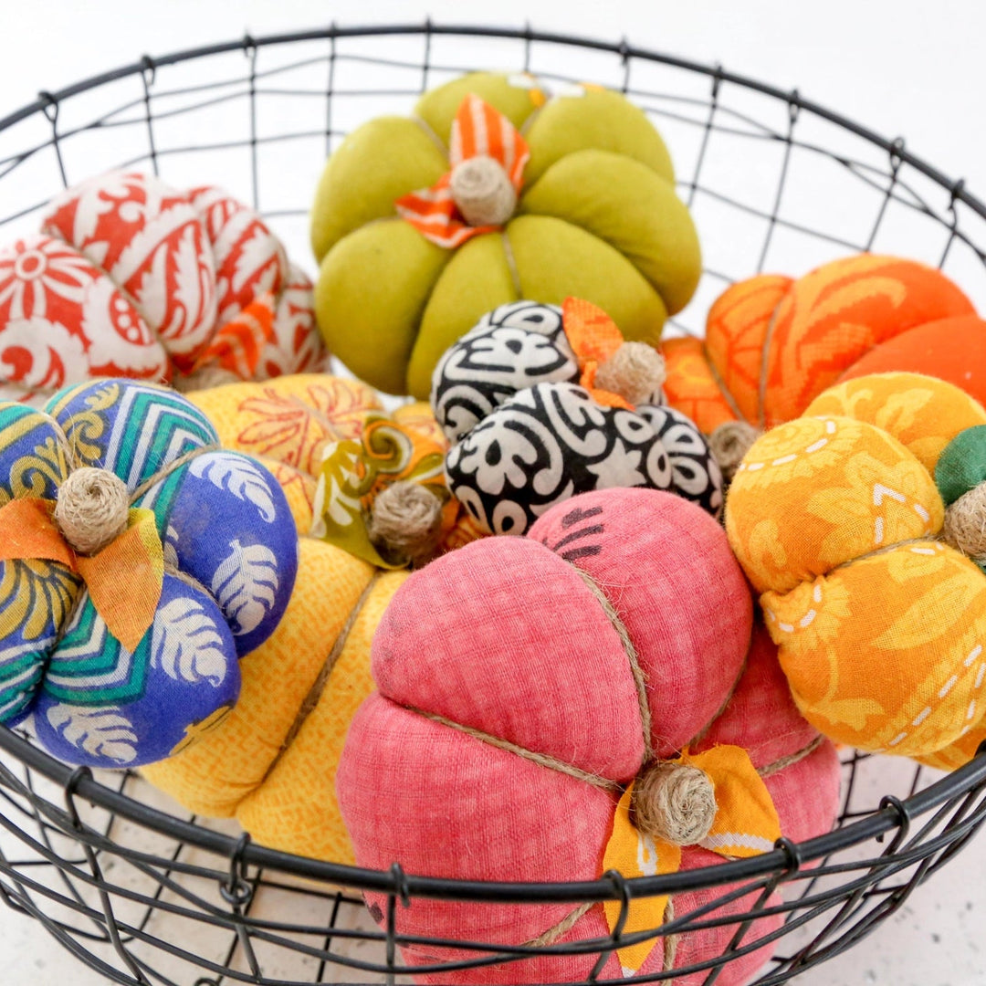 colorful sari pumpkins in a black basket on a white background