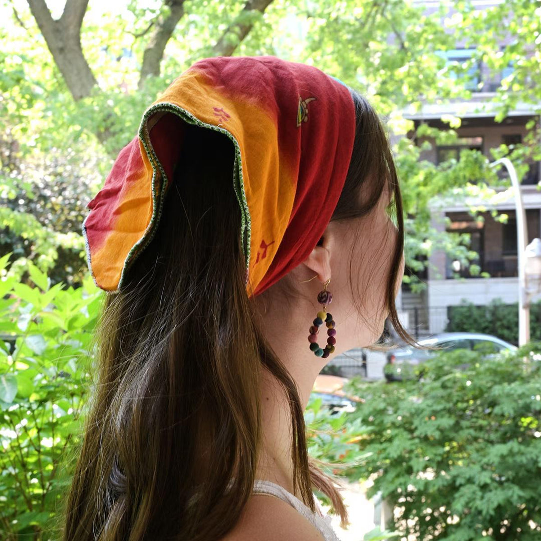 Woman wearing a colorful bandana with a blurred outdoor background