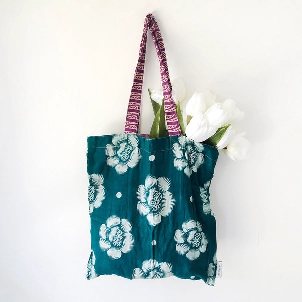 Teal Sari tote bag with floral design and pink patterned handle on a white background