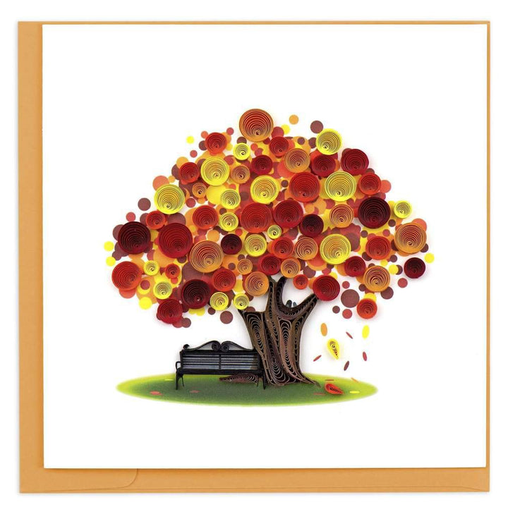 A greeting card featuring a three-dimensional paper quilled design of a tree with autumn leaves, beside a bench, on a blank background.