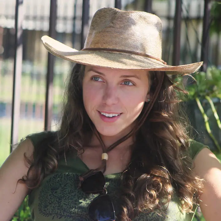 Woman wearing a straw hat and green dress outdoors