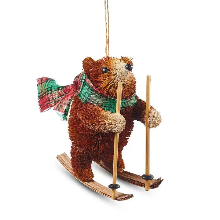 Decorative ornament of a bear skiing with skis and a plaid scarf on a white background