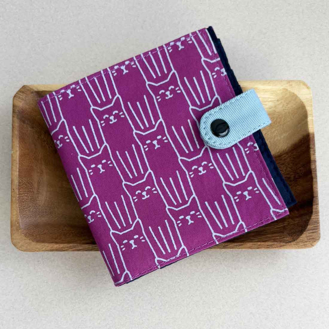 Purple wallet with white cat pattern on a wooden surface
