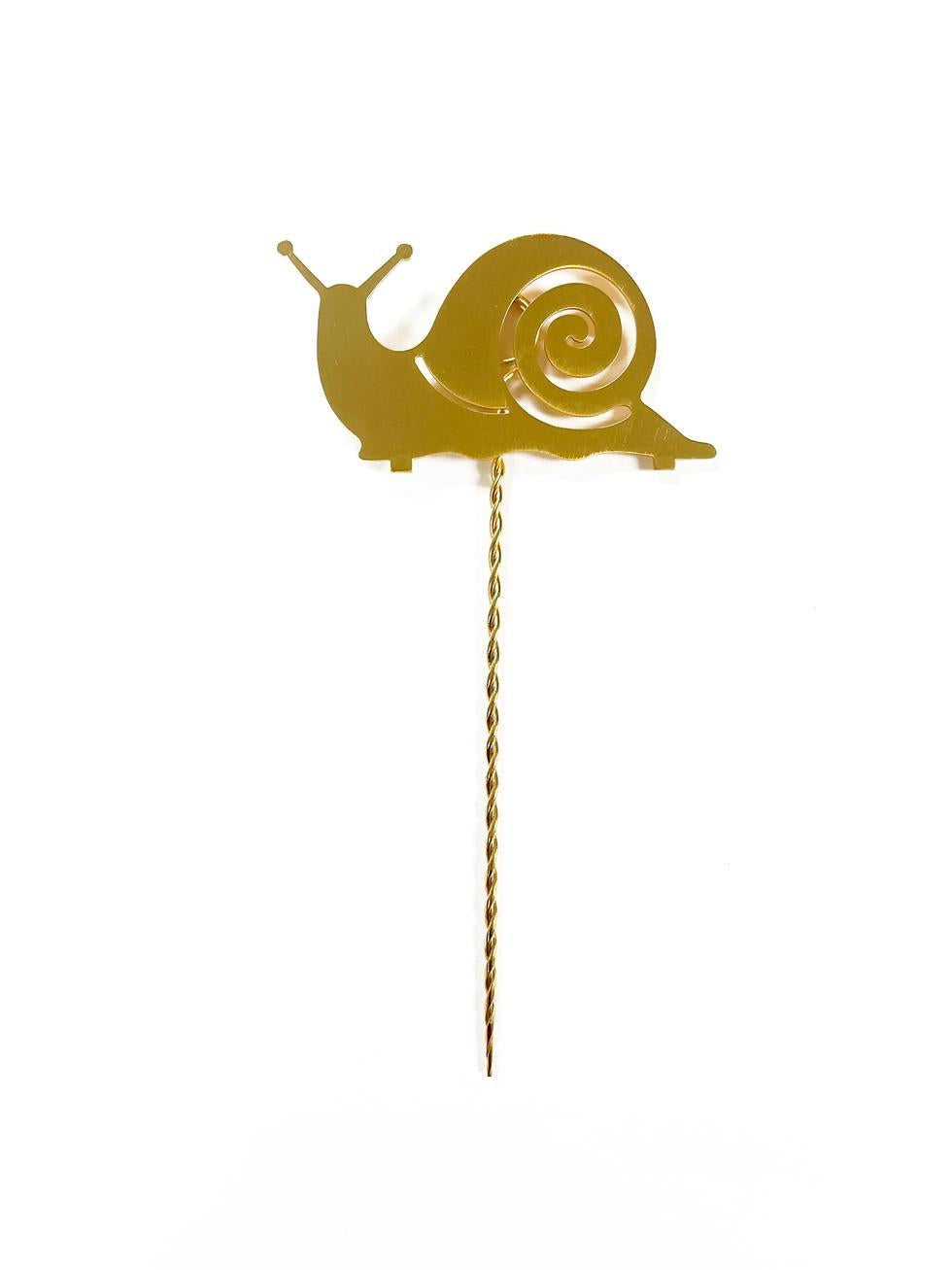 Gold snail-shaped plant stake on a white background
