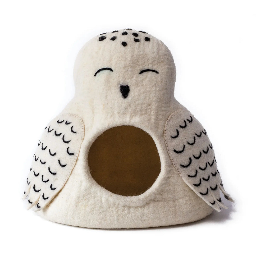 A cream-colored felt owl-shaped pet bed with black embroidered details, including closed eyes, a small black nose, and black scalloped wing patterns, shown on a plain white background.
