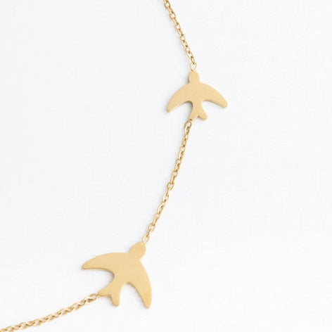 Gold bird-shaped necklace on a white background