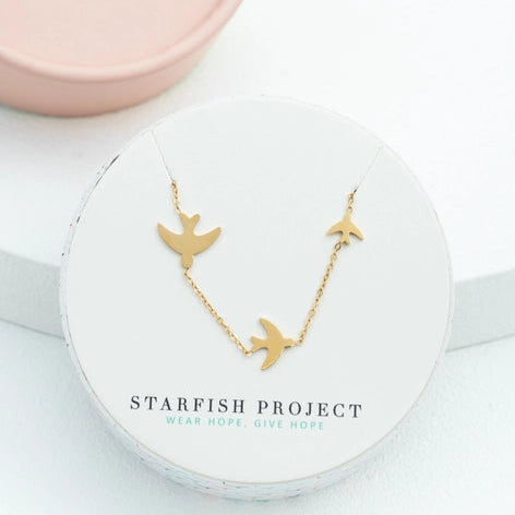 Gold necklace with starfish design on a white box with 'Starfish Project' branding.