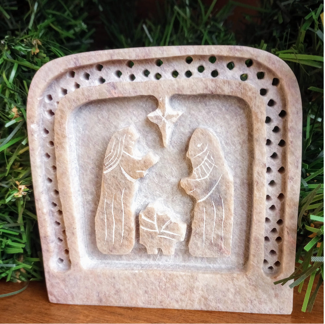 Decorative stone plaque with a nativity scene on a grassy background