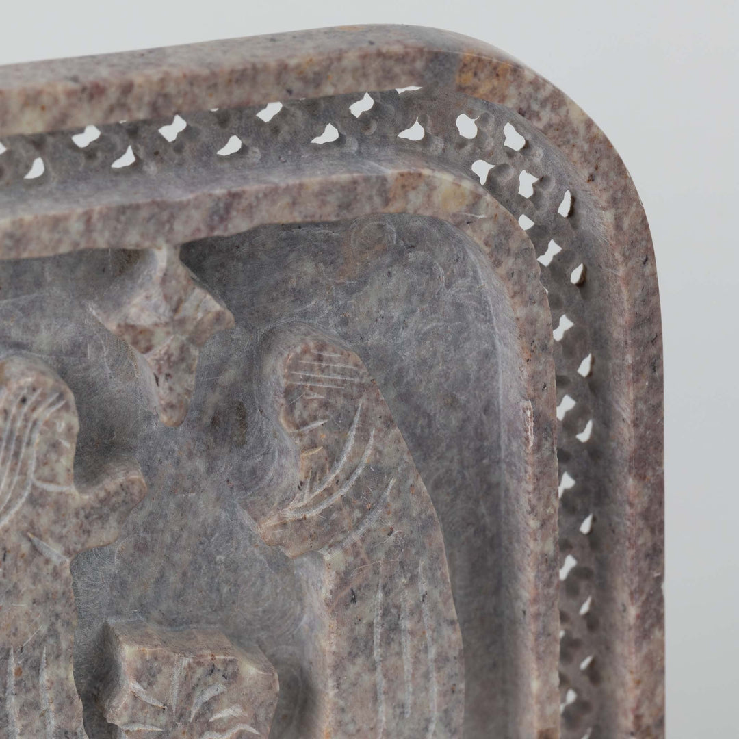 Decorative stone object with intricate nativity carving on a plain background