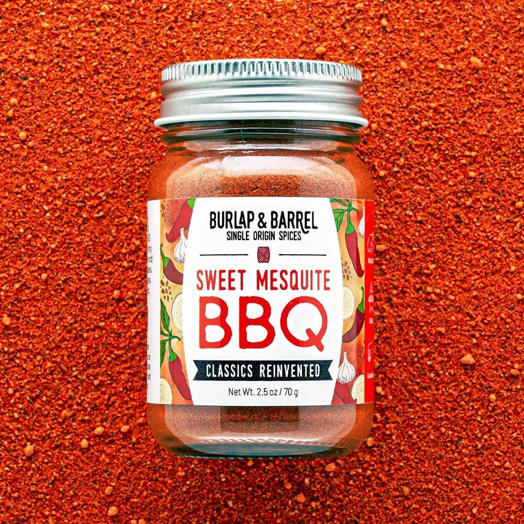 Jar of Burlap & Barrel Sweet Mesquite BBQ spice blend on a red background