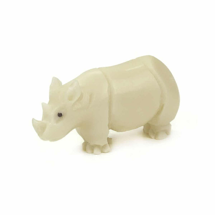 A hand-carved white tagua nut figurine of a rhino, with a smooth finish and displayed against a dark background.