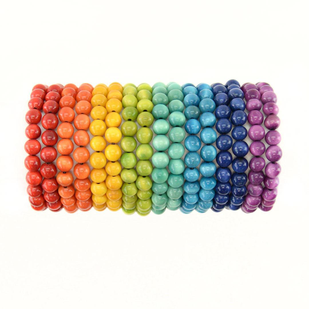 A collection of Tagua Pearl Bracelets displayed in a rainbow arrangement, showcasing a variety of bright colors.