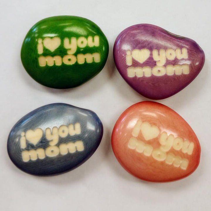 Four colorful tagua nuts with 'I love you mom' text on a white background